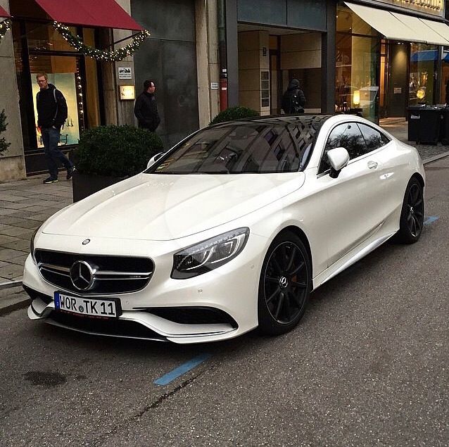 a white car is parked on the side of the road in front of a building