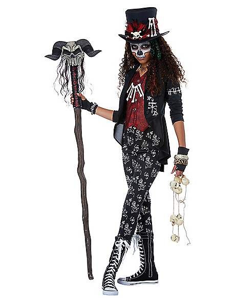 a woman dressed up as a skeleton holding a stick and wearing a top hat with skulls on it