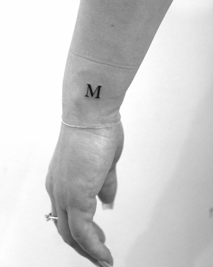 a woman's arm with the letter m tattooed on her left forearm and wrist