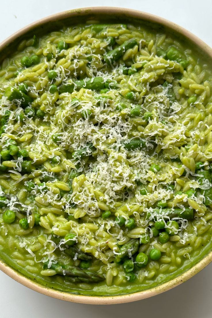 a bowl filled with pasta and peas covered in parmesan cheese