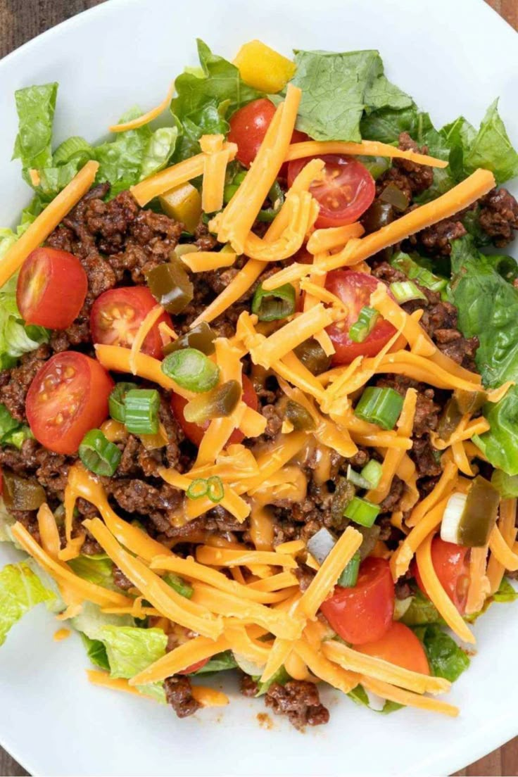 taco salad with homemade taco seasoning on a white plate, topped with lettuce and tomatoes