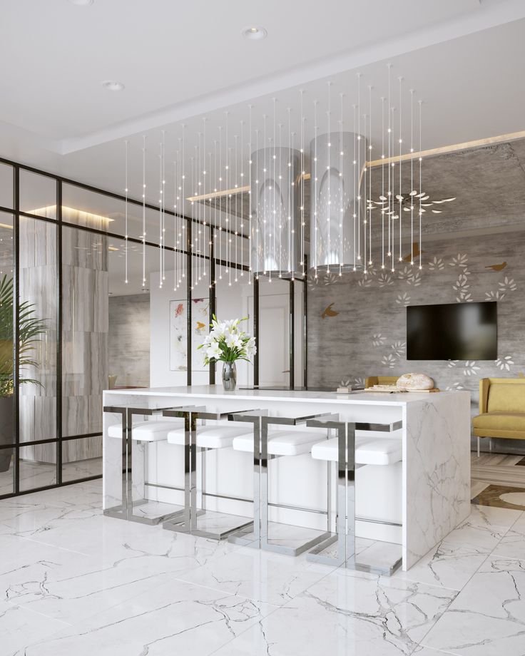 an elegant kitchen with marble counter tops and white stools in front of a television