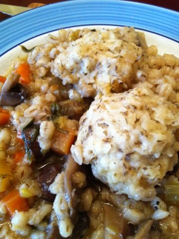 a blue and white plate topped with meat and rice covered in gravy next to a fork