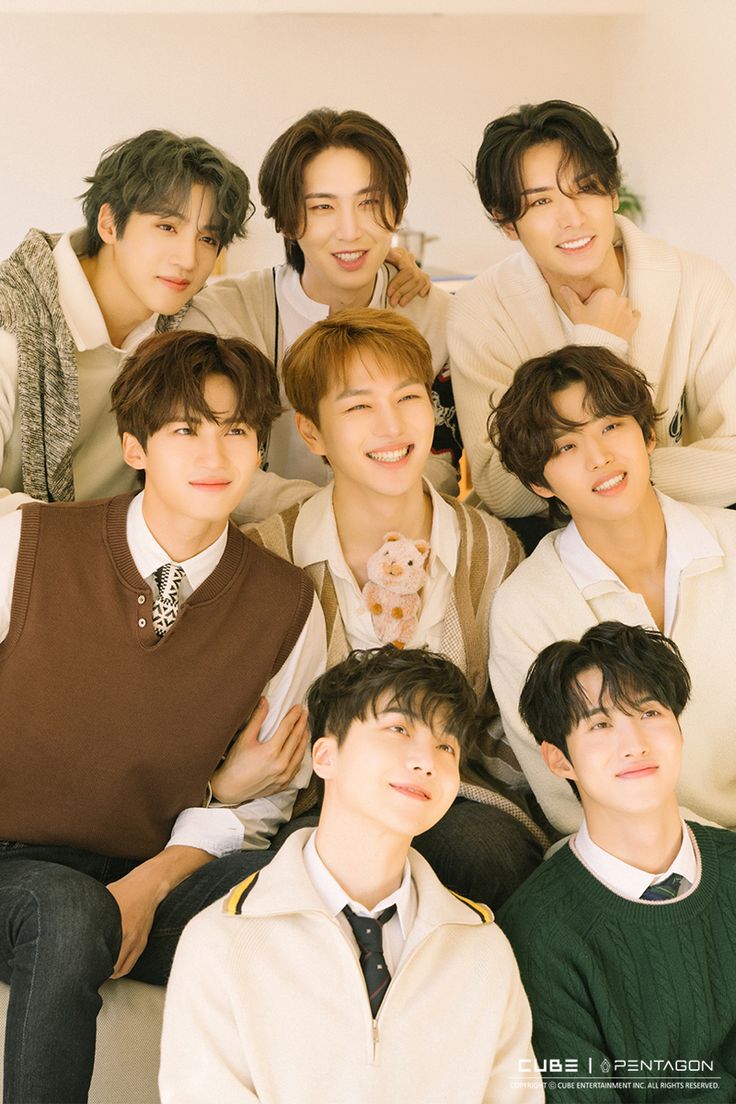 a group of young men sitting next to each other in front of a white wall