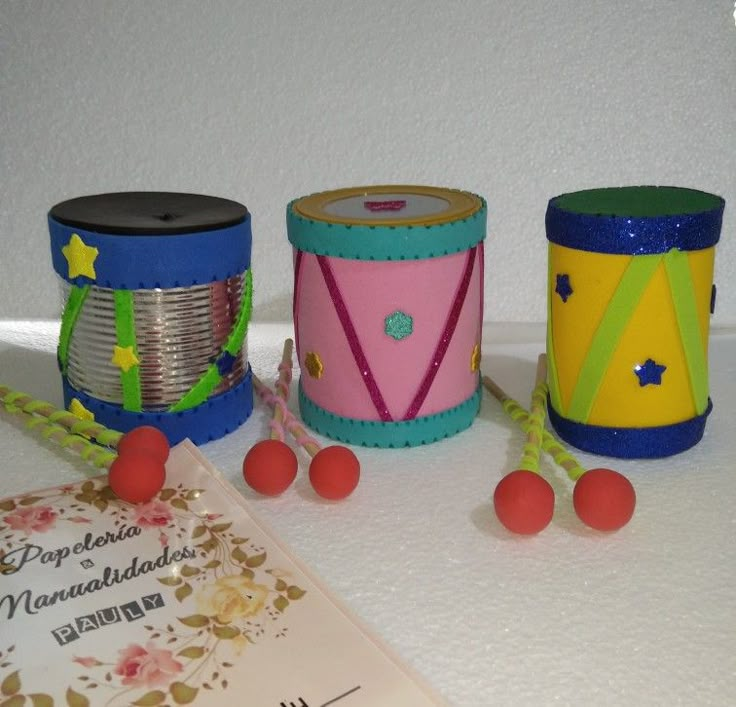 there are three different colored drums on the table next to a card and some beads