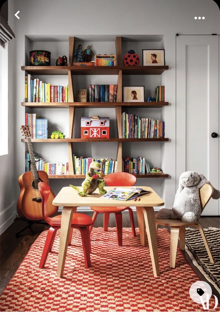 a room with bookshelves, chairs and a table in front of a teddy bear