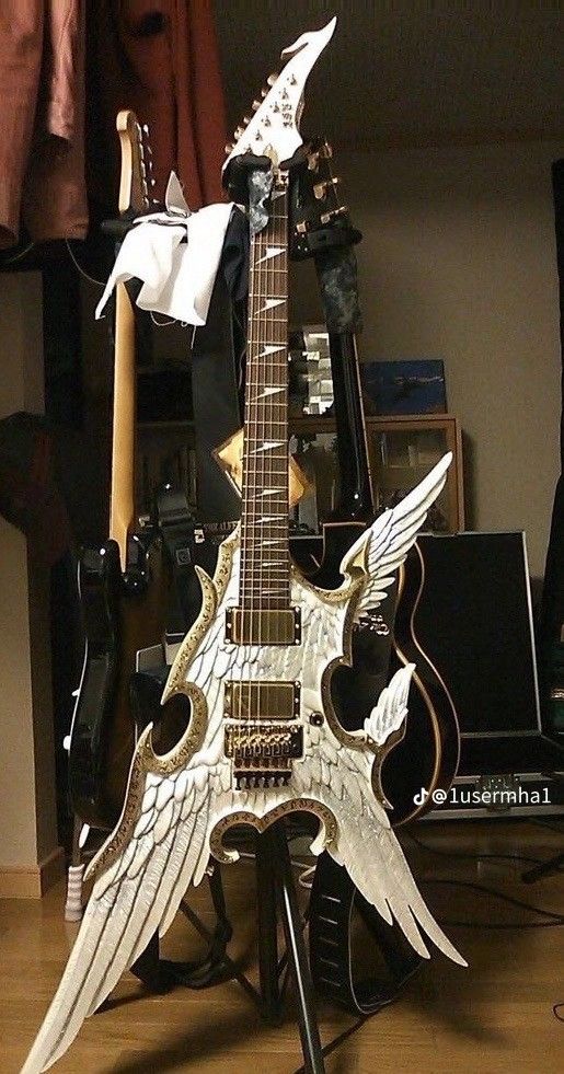 an electric guitar with angel wings on it's body is sitting on a stand