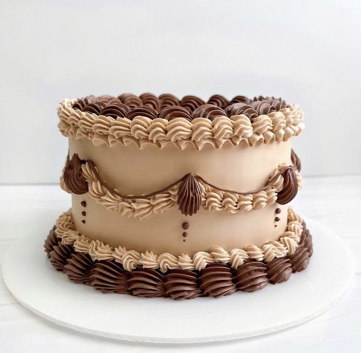 three tiered cake sitting on top of a white plate covered in chocolate frosting