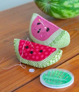 two watermelon slices are sitting on the table next to a spool of thread