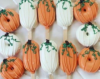 there are many pumpkins on the sticks with icing and green sprinkles