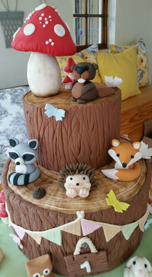 a birthday cake made to look like a tree stump with animals and mushrooms on it