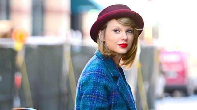 a woman in a blue coat and hat is walking down the street with her handbag