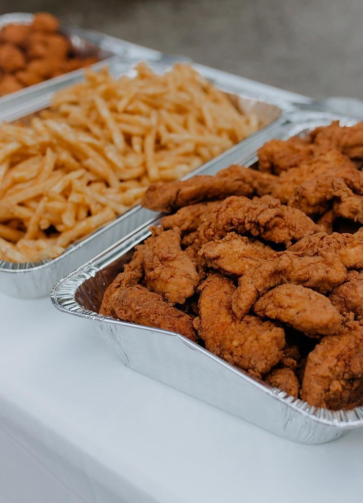 two tins filled with fried food sitting on top of a white table next to each other