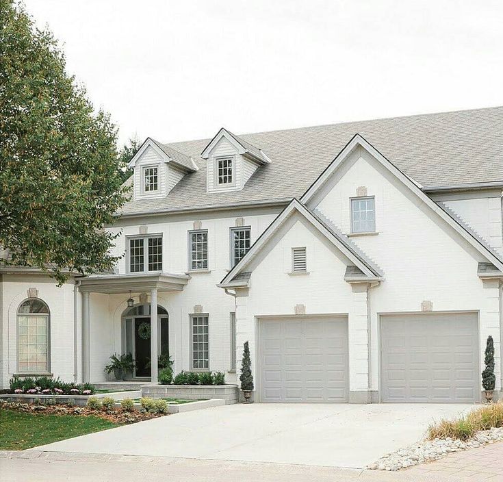 a large white house with two garages on the front and one car parked in front