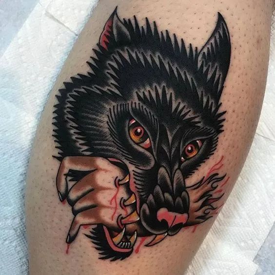 a close up of a person's leg with a wolf tattoo on the thigh