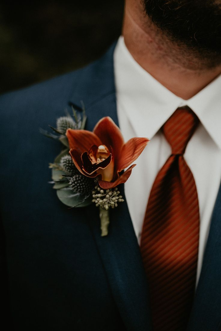 a man in a suit and tie with an orange boutonniere on his lapel