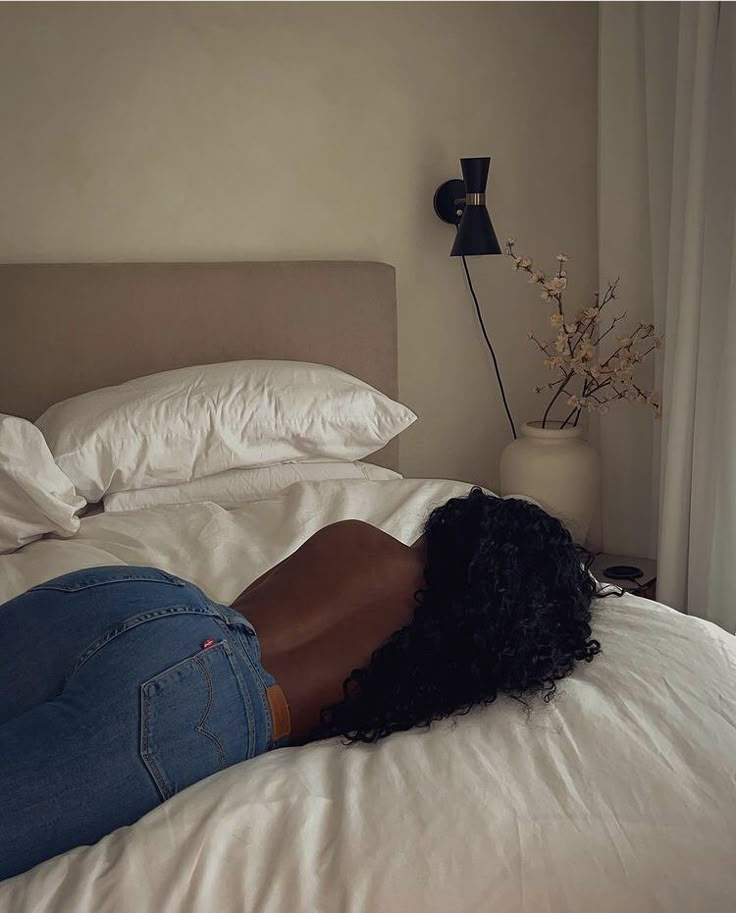 a woman laying on top of a bed next to a window