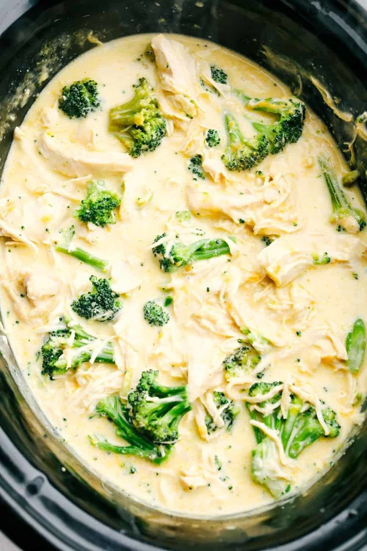 a crock pot filled with broccoli and chicken in cream sauce on top of a stove