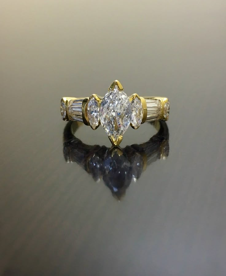 an engagement ring with three pear shaped diamonds on the side, set in yellow gold