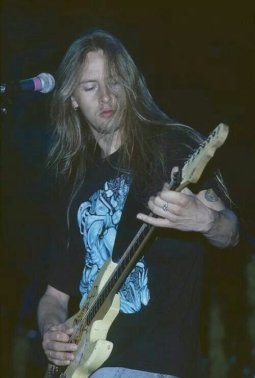 a man with long hair playing an electric guitar