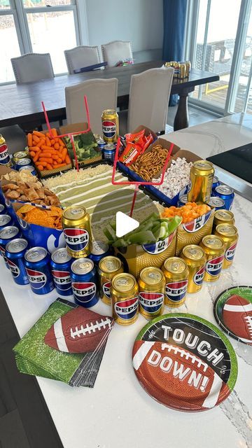 a football themed party spread with beer and snacks on a table in front of large windows