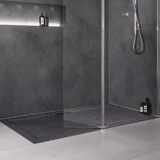 a bathroom with grey walls and flooring has a glass shower door that is open