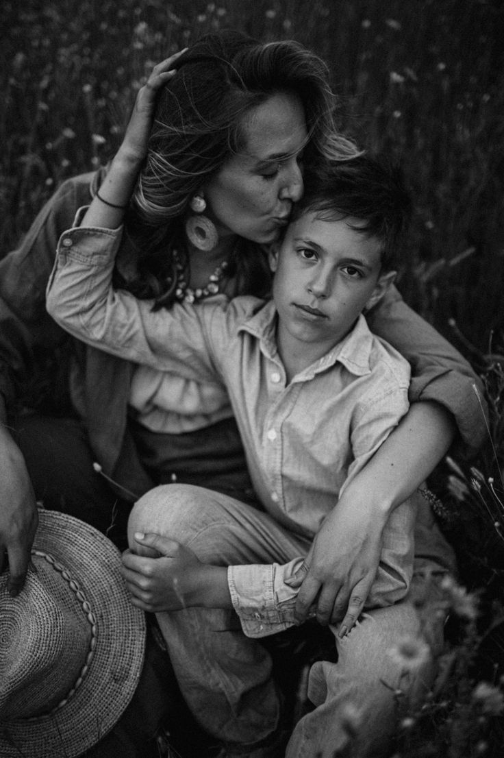 a woman sitting next to a child on top of a field