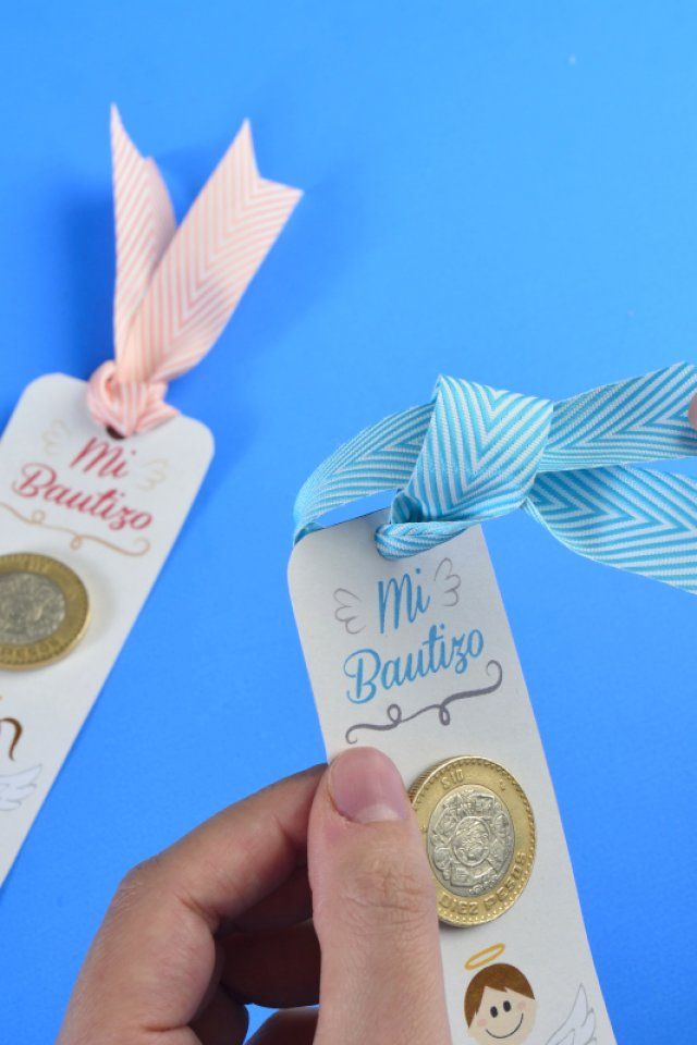 someone is holding two small tags with ribbons attached to them, one has a coin and the other has a bow