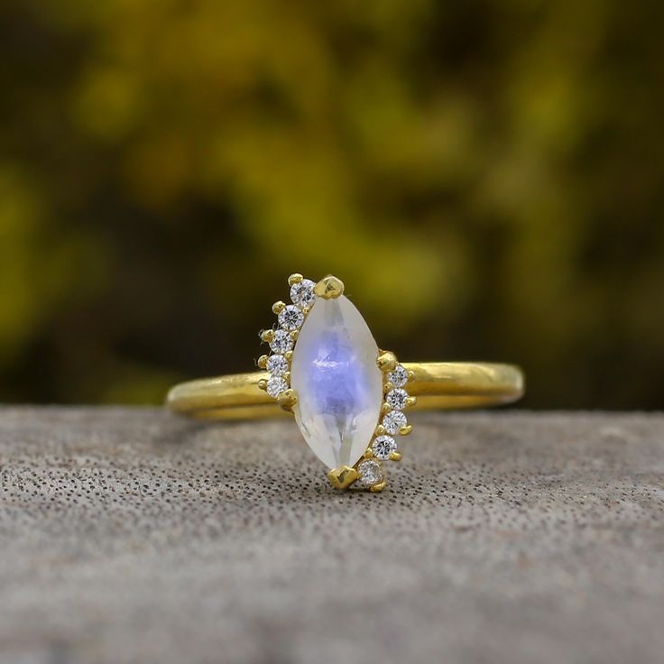 Fit for a princess, our ring with the beautiful Rainbow Moonstone the is an exquisite ring perfect for a wedding anniversary, pre-engagement ring, or as something special for a loved one.                                                         ►Gemstone: Natural Rainbow Moonstone ►Base Metal: Solid 14k Gold  ►Plating: 18k Gold Vermeil ★Natural Rainbow Moonstone stone cannot be always the same, gemstone colour may change in different light/background condition. ★Gemstone size: ★Center Stone - 5 m Celestial Style Moonstone Wedding Ring In 14k Gold, Celestial 14k Gold Moonstone Wedding Ring, Celestial Style 14k Gold Moonstone Wedding Ring, Celestial Diamond Crystal Wedding Ring, Celestial Style Diamond Crystal Wedding Ring, Marquise Gold Topaz Ring For Wedding, Celestial Moonstone Halo Ring For Wedding, Celestial Halo Moonstone Ring For Weddings, Celestial Halo Moonstone Wedding Ring