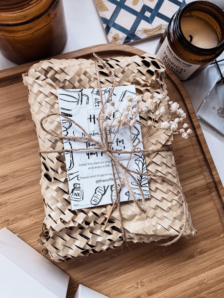 a wrapped gift sitting on top of a wooden cutting board next to candles and other items