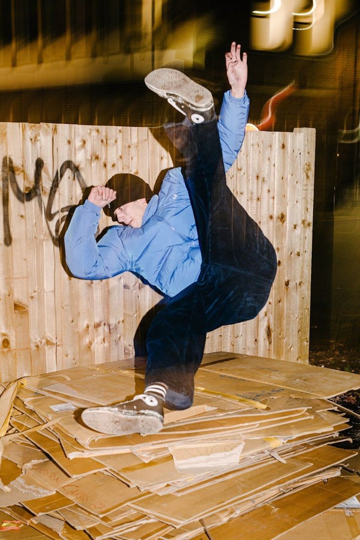 a man in blue shirt doing a trick on a skateboard with his hands up