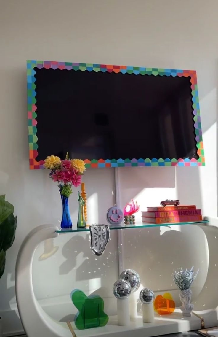 a white sink sitting under a flat screen tv mounted on a wall next to a potted plant