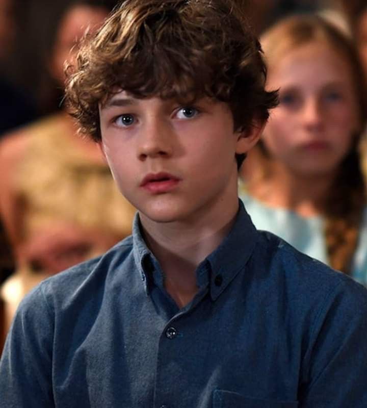 a young boy is staring at the camera in front of an audience with his hand on his hip