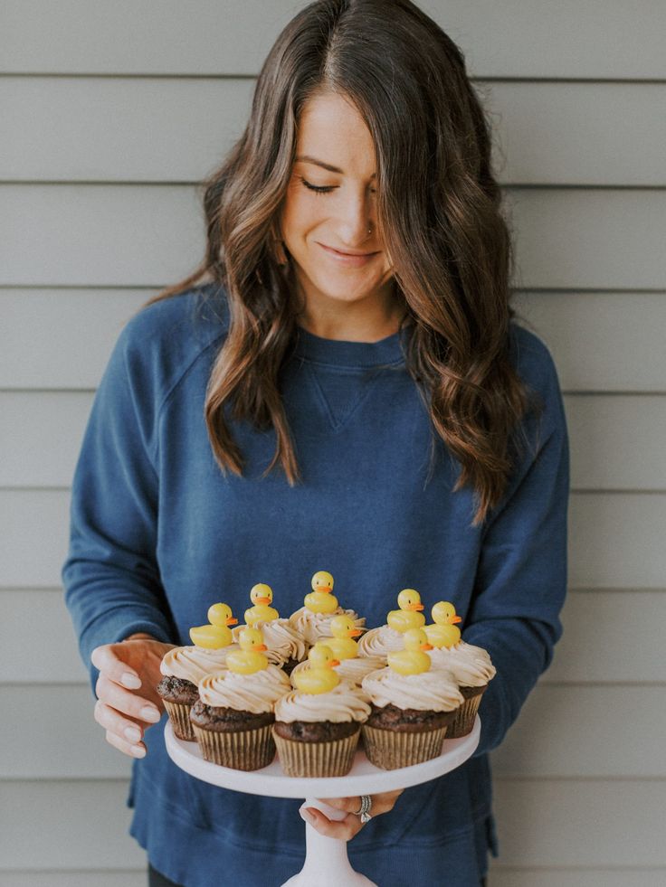 a woman holding a tray with cupcakes on it