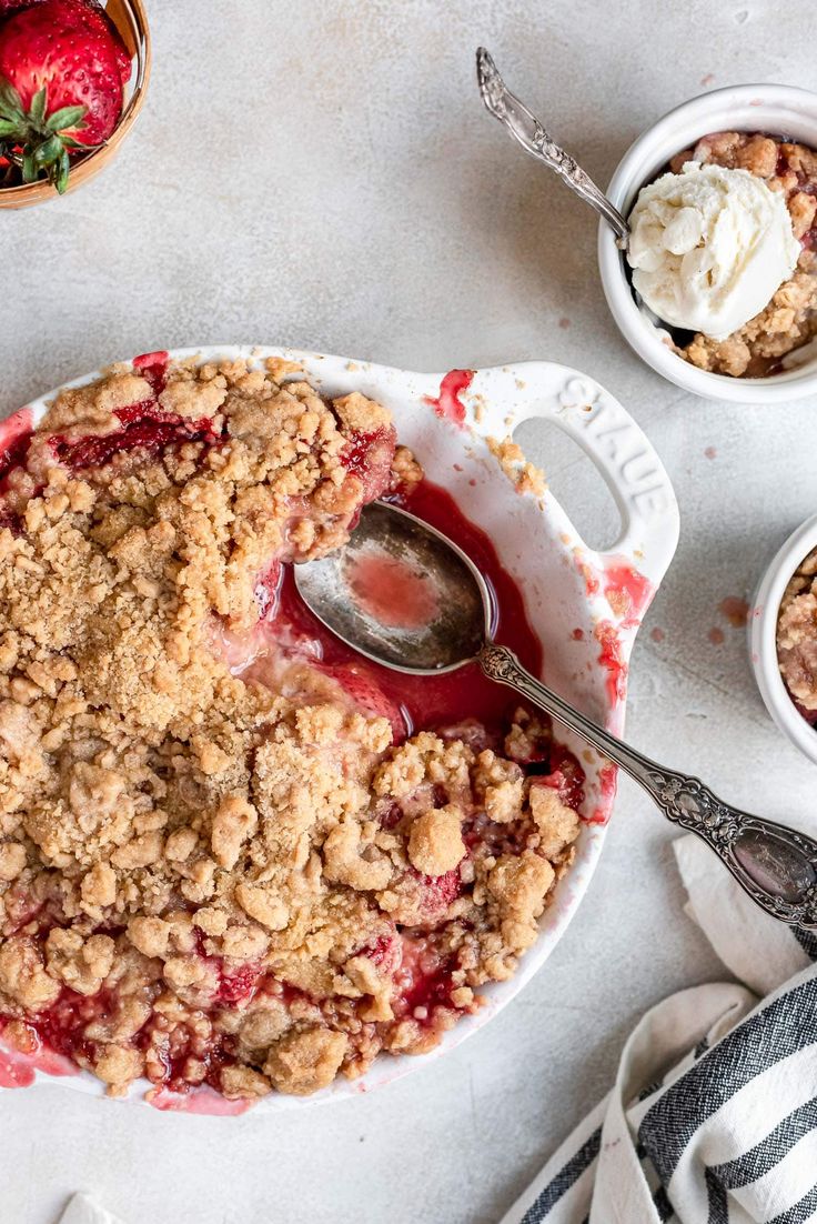 an apple crumbled dessert is served with ice cream and strawberries on the side