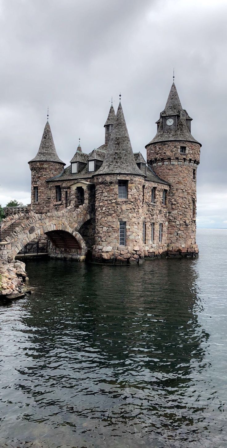 an old castle sitting on top of a body of water next to a stone bridge