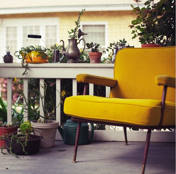 a yellow chair sitting on top of a porch next to potted plants