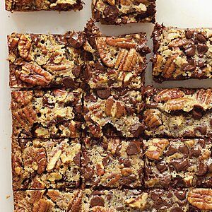 chocolate pecan bars stacked on top of each other with nuts in the middle and more pecans scattered around them