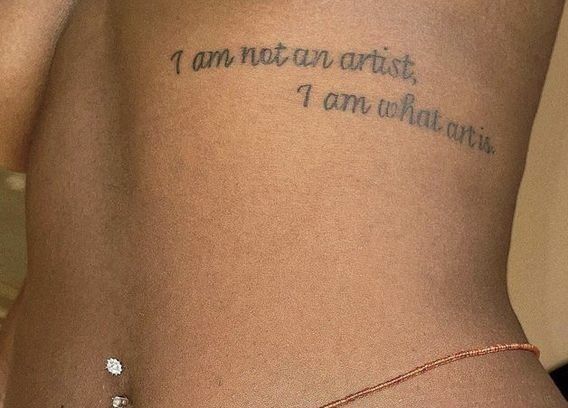 a woman with a tattoo on her back saying i am not an artist