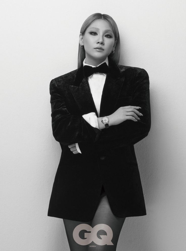 a black and white photo of a woman in a tuxedo with her arms crossed