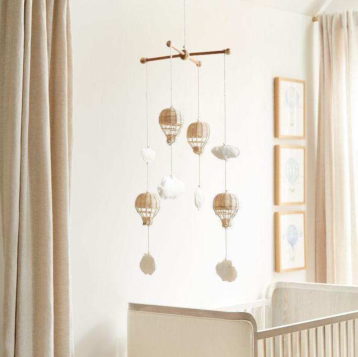 a baby crib in a white room with hanging decorations on the wall and curtains