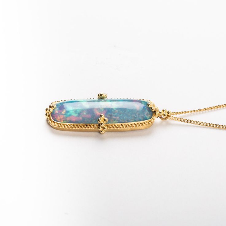 This remarkable teardrop-shaped Ethiopian Opal glimmers with the delicate rainbow iridescence of morning mist caught in a sunbeam, with blue hues above that fade into warm shimmers of orange and red below. Suspended from an 18K yellow gold chain, this one-of-a-kind gemstone is set in a handmade gold bezel with braided detail and granulated prongs. One of a kind. Technical Details Metal: 18k yellow goldEthiopian Opal: 7.46 cts. x mmPendant Size (not including bail): 30 x 12.5 mmChain: can be worn Yellow Gold Ethiopian Opal Necklace, Gold Ethiopian Opal Pendant Necklace, Ethiopian Opal Pendant Necklace Gift, Hallmarked Ethiopian Opal Pendant Jewelry, Ethiopian Opal Multi-stone Jewelry In Yellow Gold, Morning Mist, Yellow Gold Chain, Handmade Gold, Blue Hues