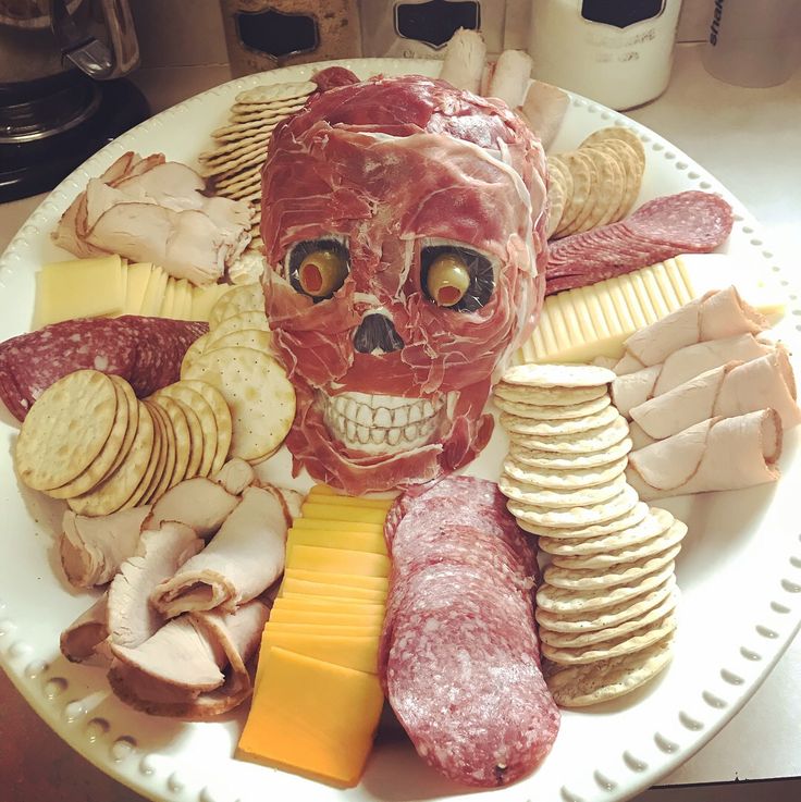 a plate with meat, cheese and crackers on it is decorated like a human head