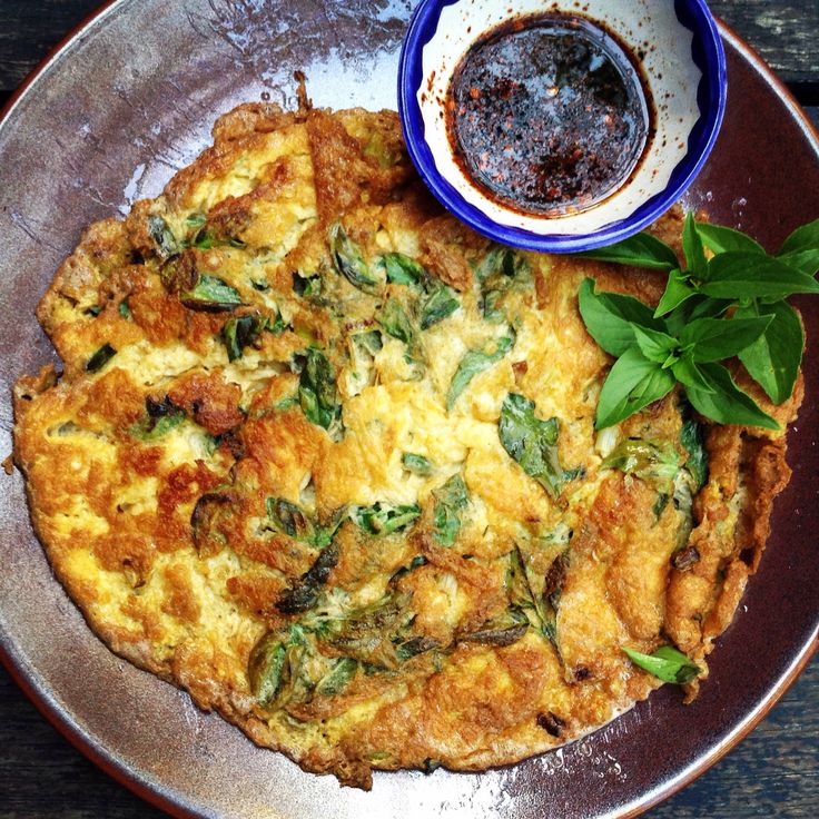 an omelet is on a plate with some dipping sauce