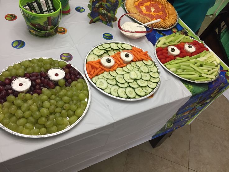 three plates filled with food on top of a table covered in grapes and cucumbers