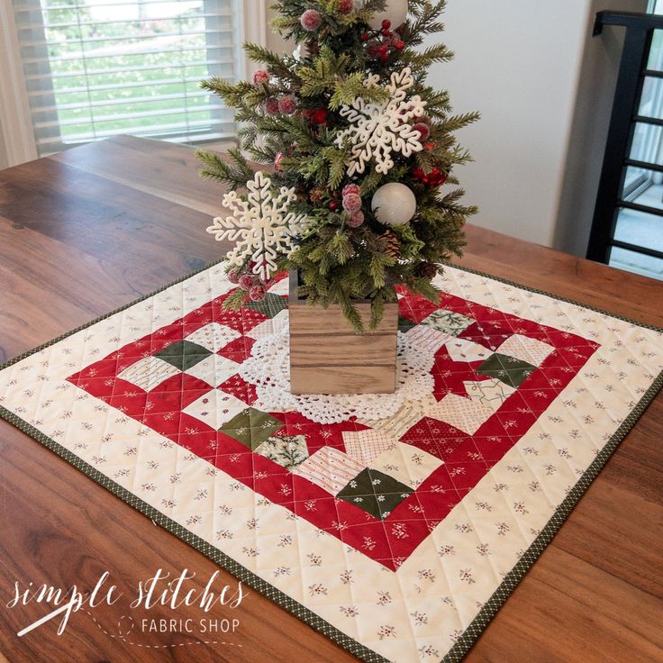 a small christmas tree on top of a table with red and white quilted placemats