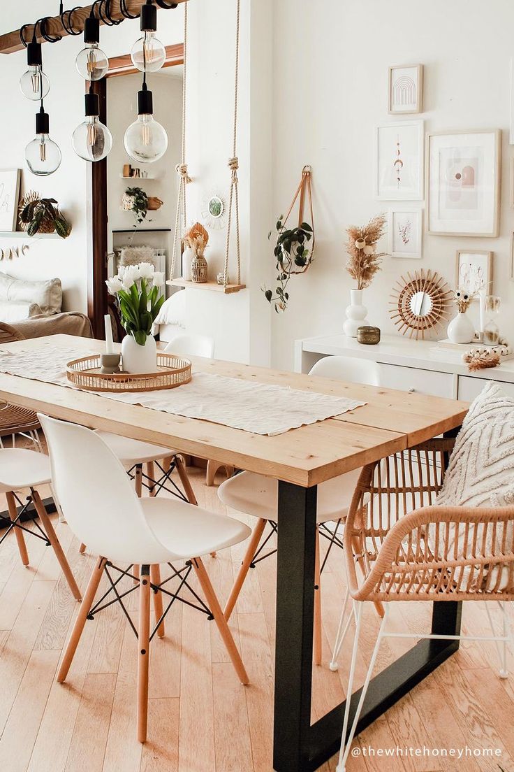 a dining room table surrounded by white chairs and potted plants in the middle of it