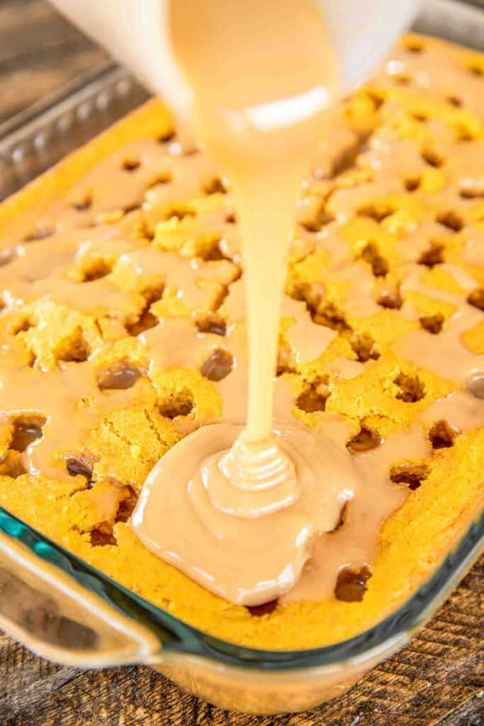 someone pouring peanut butter on top of a chocolate chip cookie in a glass baking dish