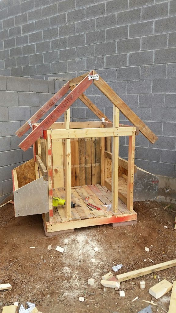 a dog house made out of wooden pallets and wood planks on the ground