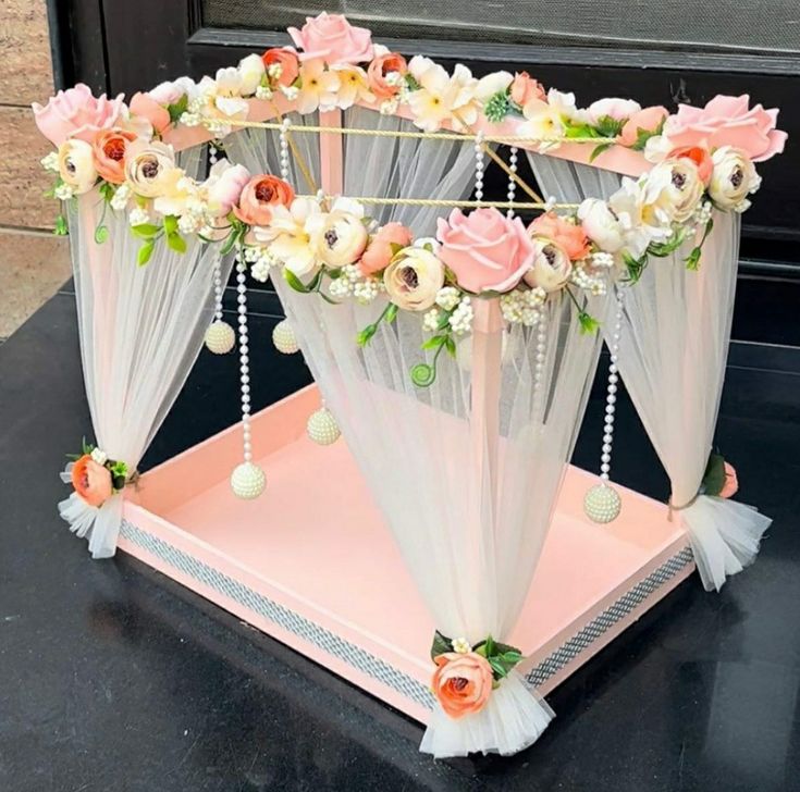 a pink and white canopy bed with flowers on the top is sitting in front of a black door